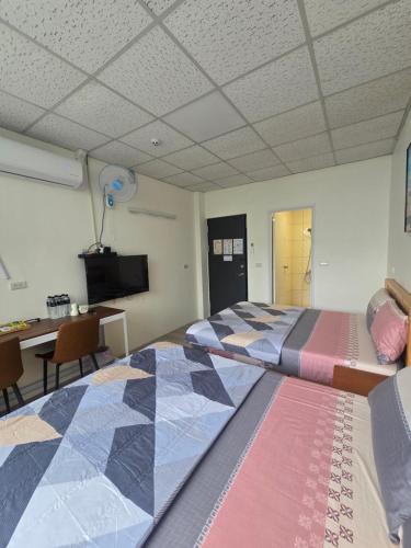 a bedroom with two beds and a desk and a tv at 南田旅宿親子商務 in Fengyuan