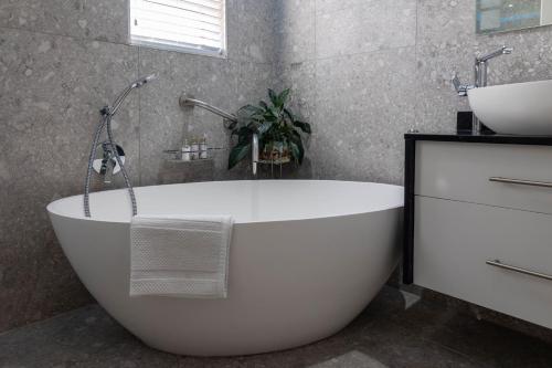 a white bath tub in a bathroom with a sink at Bon A Vie Self-catering and b&b Gonubie Full Solar Power, no load shedding! in Gonubie