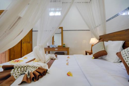 a bedroom with a large white bed with curtains at Kubu Kapas Bali in Ubud