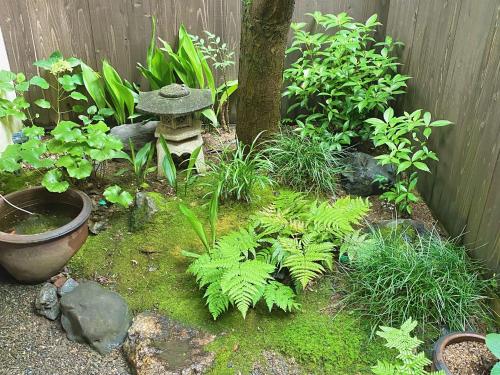 a garden with plants and a tree in a fence at Guesthouse Kioto in Kyoto
