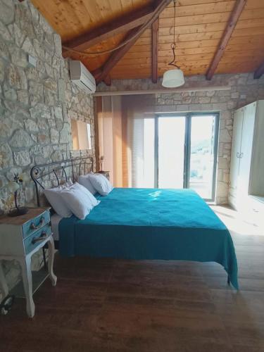 a bedroom with a blue bed with a stone wall at Villa Lydia in Meganisi