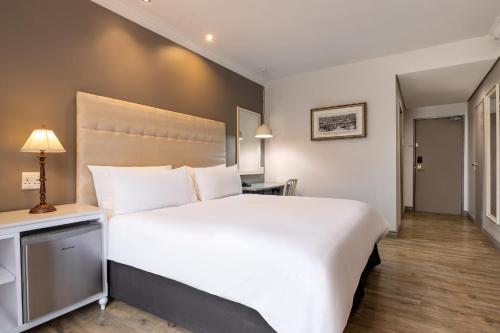 a large white bed in a hotel room at Protea Hotel by Marriott Kimberley in Kimberley