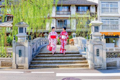 two women in kimonos walking down some stairs at Ooedo Onsen Monogatari Premium Kinosaki in Toyooka