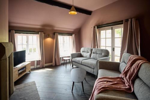 a living room with a couch and a tv at Jasmine Cottage - Sands Farm in Wilton