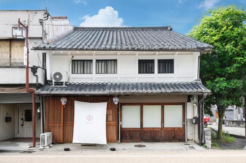 a small white house with a large garage at ann長良 Machiya Private Villa ann Nagara 築130年古民家で長良川と岐阜城を満喫 無料駐車場4台完備 無人チェックイン in Gifu