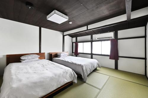 a bedroom with two beds and a window at ann長良 Machiya Private Villa ann Nagara 築130年古民家で長良川と岐阜城を満喫 無料駐車場4台完備 無人チェックイン in Gifu
