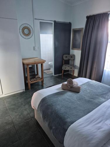 a bedroom with a bed and a table and a chair at Silver’s Rest Beach House in Clareport