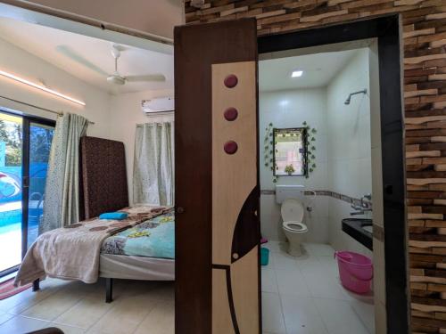 a bedroom with a bed and a bathroom with a toilet at Trupti Villa & Cottages-Nagaon- Three BHK Villa in Alibaug