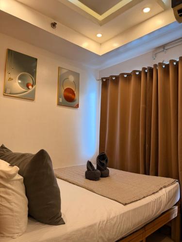 a bedroom with a bed with a curtain and shoes at Shell Residences MOA by Jersey in Manila