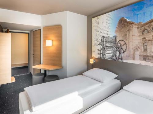 a room with two beds and a painting on the wall at B&B HOTEL Düren in Düren - Eifel