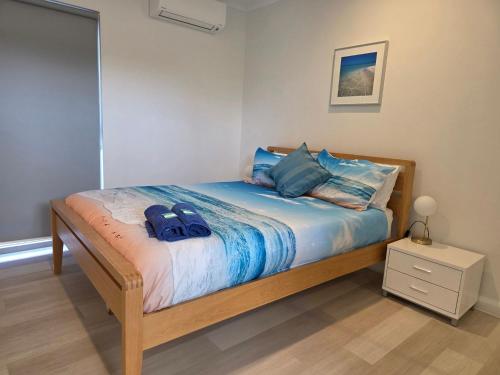 a bedroom with a bed with two blue bags on it at Waves at Jurien, Villa 9-23 Dalton Street in Jurien Bay
