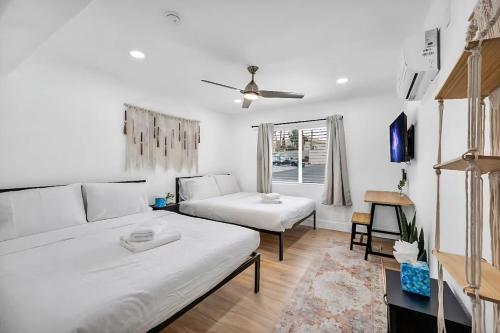 a white living room with two beds and a window at Vegas Haven Pool Spa Game Room in Las Vegas