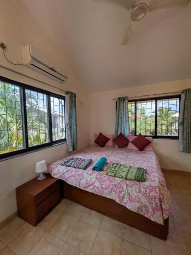 a bedroom with a large bed and windows at Trupti Villa & Cottages-Nagaon- Three BHK Villa in Alibaug
