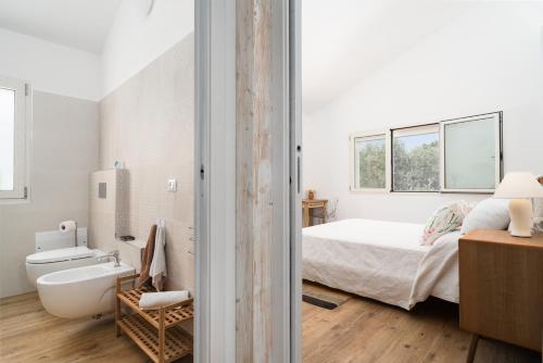 a white bathroom with a bed and a bath tub at Villa Piricone in Orosei