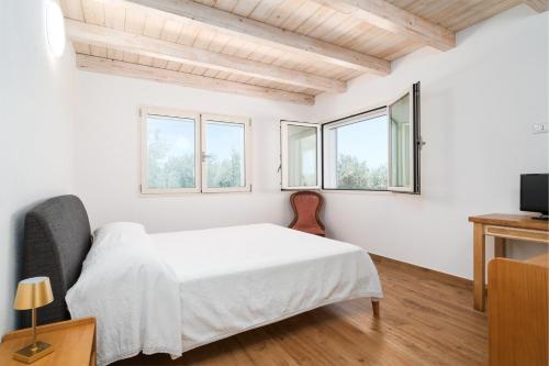 a white bedroom with a bed and windows at Villa Piricone in Orosei