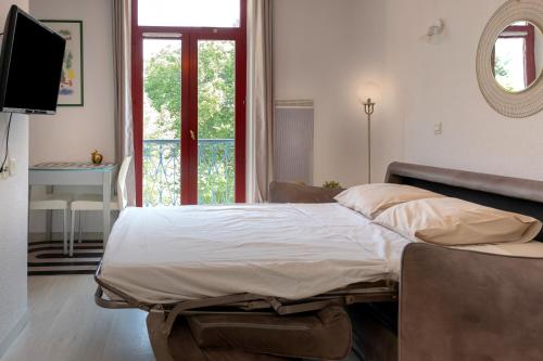 a bedroom with a bed and a television and a window at Studio Le Splendid 3 Hôtel étoiles in Allevard