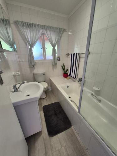 a bathroom with a sink and a tub and a toilet at Silver’s Rest Beach House in Clareport
