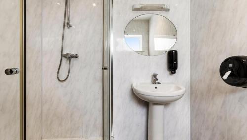 a bathroom with a sink and a mirror and a shower at Sandy Lodge Hotel Newquay in Newquay