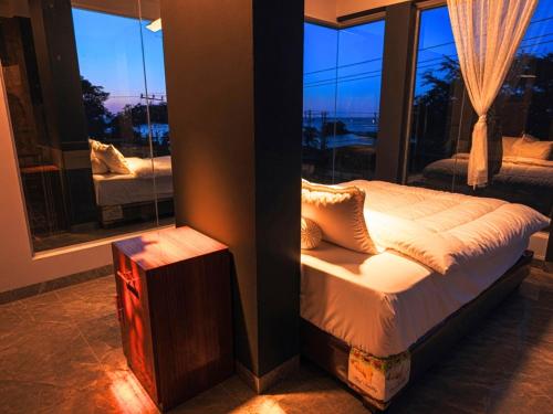 a bedroom with a bed and a large window at Teupin Layeu Hotel in Iboih