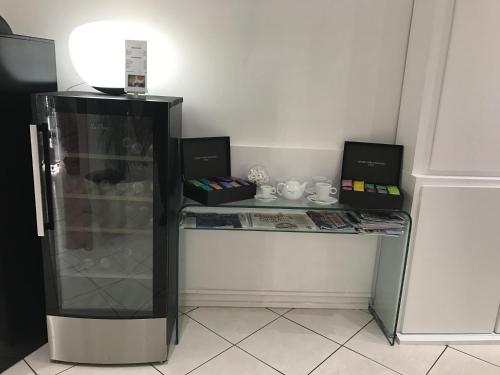 Cette chambre comprend un bureau et un réfrigérateur en verre. dans l'établissement Hôtel Le Capitole, à Toulouse
