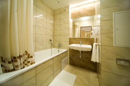 uma casa de banho com um lavatório e uma banheira e um lavatório em Hotel Krystal em Praga