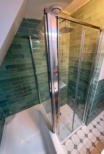 a shower in a bathroom with green tiles at Bosvilla in Harfsen