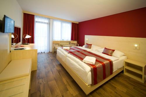una camera con un grande letto con una parete rossa di Hotel Krystal a Praga