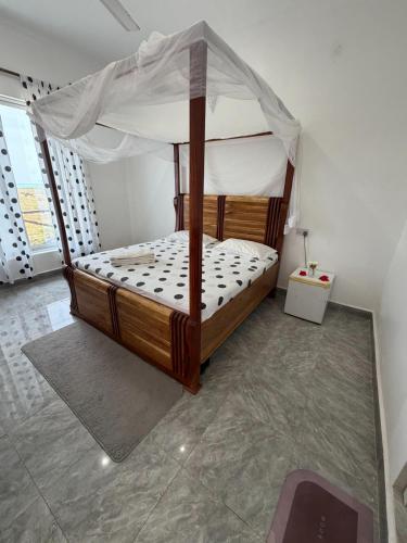 a wooden bed with a canopy in a room at Nyota Apartment in Nungwi