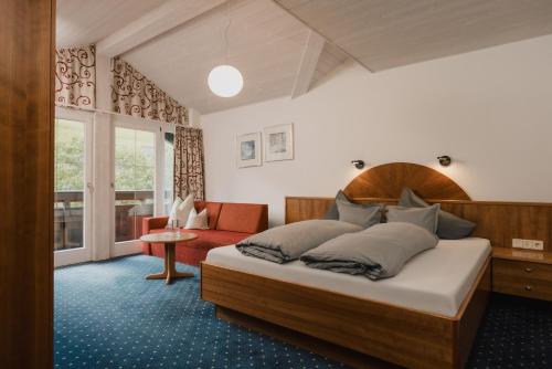 a bedroom with a large bed and a red couch at Appartement Désirée inkl der SUPER SOMMER CARD im SOMMER 2026 in Serfaus