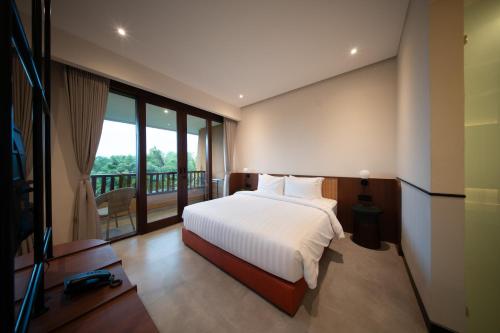 a bedroom with a bed and a balcony at Padang Padang Inn in Uluwatu