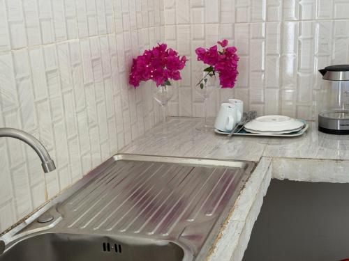 a kitchen sink with pink flowers on a counter at Nyota Apartment in Nungwi