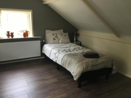 a bedroom with a bed in a attic with a window at 't Skoallehus in Steggerda