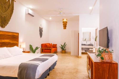 a bedroom with a bed and a living room at Collection O Kaab Downtown Tulum in Tulum