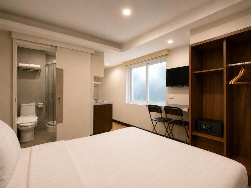 a bedroom with a bed and a bathroom with a toilet at Suk41 Bangkok Hotel in Bangkok
