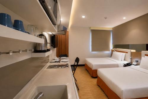 a room with two beds and a kitchen with a sink at Suk41 Bangkok Hotel in Bangkok