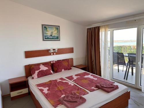 a bedroom with a large bed with a balcony at Hotel Filland in Sozopol