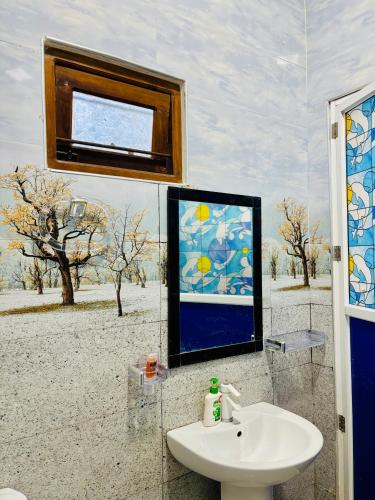 a bathroom with a sink and a painting of a desert at Viyona Guest House in Trincomalee