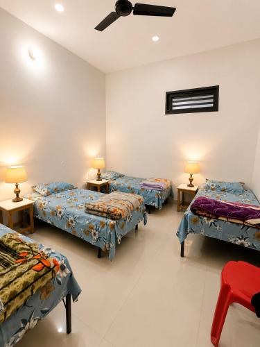 a room with three beds and two tables with lamps at Mountain View in Chamba