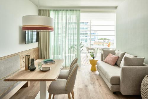 a living room with a couch and a table at Falkensteiner Residences Jesolo in Lido di Jesolo