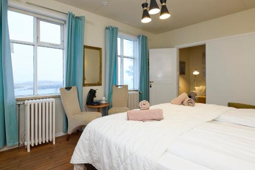 a bedroom with two beds and chairs and windows at Englendingavík Homestay in Borgarnes