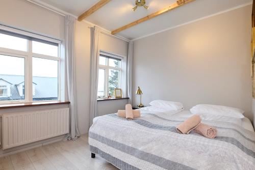 a white bedroom with a large bed with two windows at Englendingavík Homestay in Borgarnes