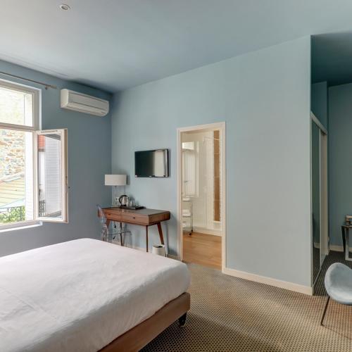 a bedroom with a bed and a desk and a window at Le Pavillon d'Enghien, Vichy Centre in Vichy