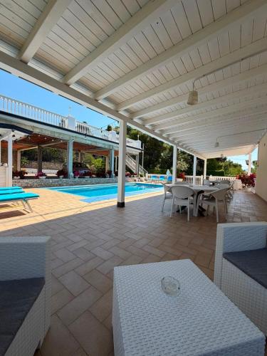 a patio with a white pergola next to a pool at Hotel Gezimi in Shëngjin