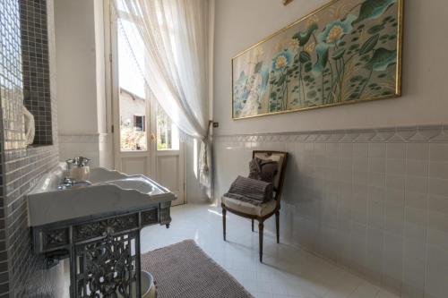 a bathroom with a sink and a chair next to a window at Villa Messori Spa in Castelvetro di Modena