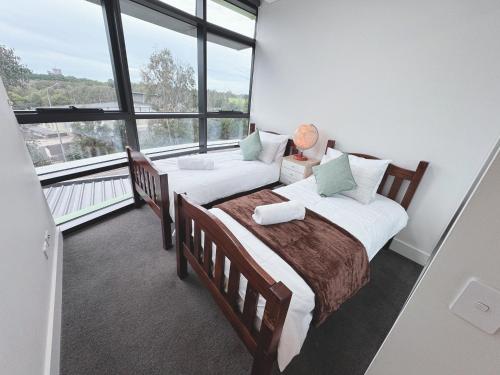 a bedroom with two beds and a large window at Floor-to-Ceiling Park View Oasis at Olympic Park Free Parking Sleeps 5 in Sydney