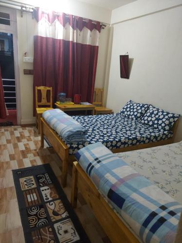 a bedroom with two beds and a window with a curtain at Za Homestay in Cherrapunji