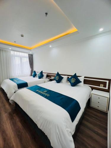 two beds in a hotel room with blue and white at Bảo Nhi Paradise Hotel in Làng Môn