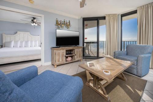 a living room with a tv and a couch and chairs at Phoenix VI 61004 in Orange Beach