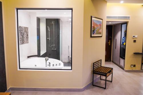 a bathroom with a tub in a window with a chair at Hotel Hillview Islamabad in Islamabad