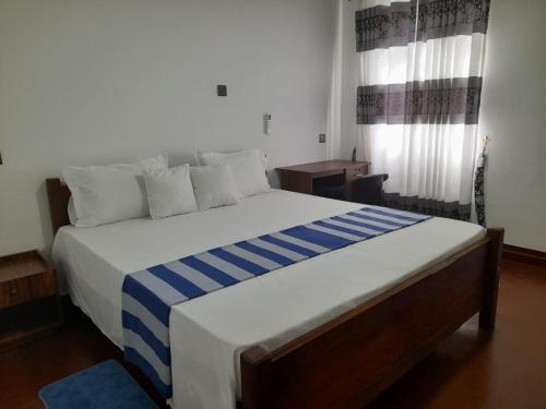 a bedroom with a large bed with blue and white sheets at Avona Villa in Bopitiya